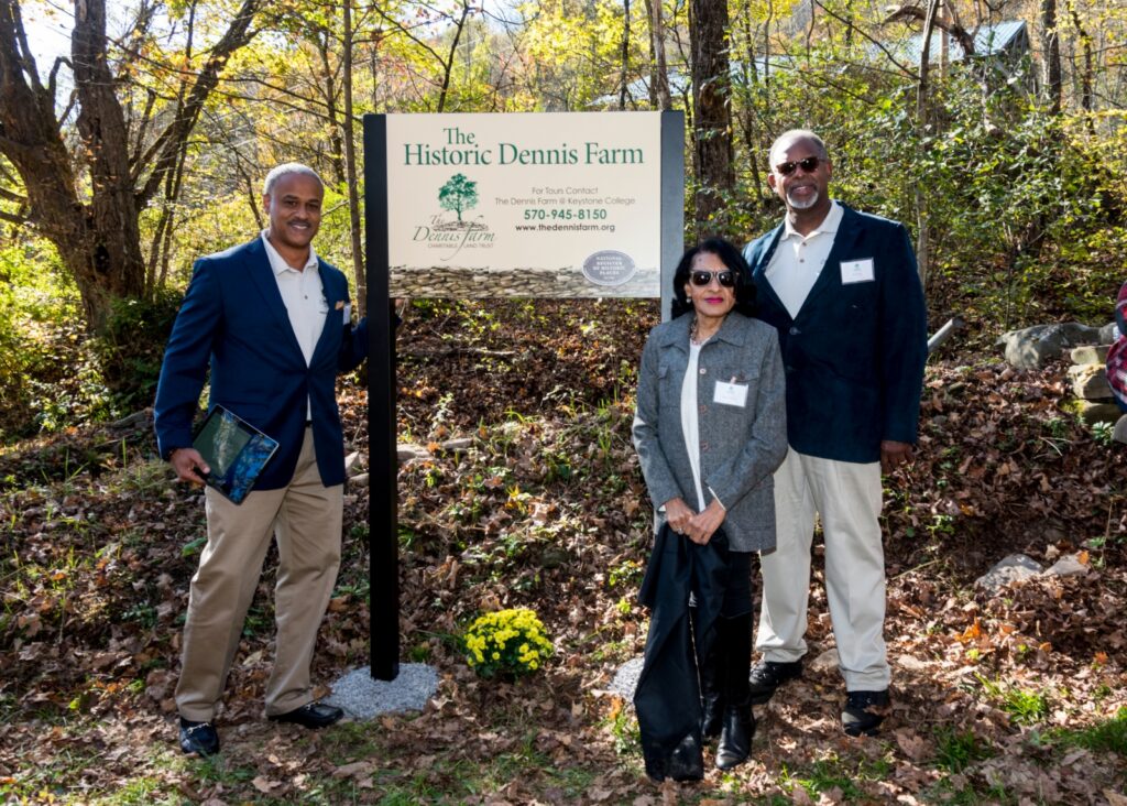 3 people standing at a sign